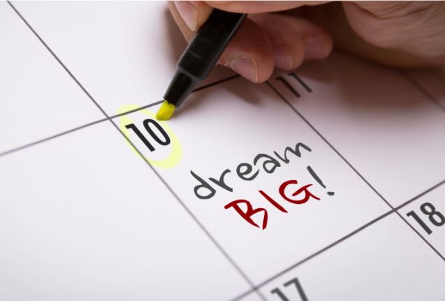 A close-up of a calendar with the words 'Dream Big!' highlighted in yellow, symbolizing goal setting and ambition.