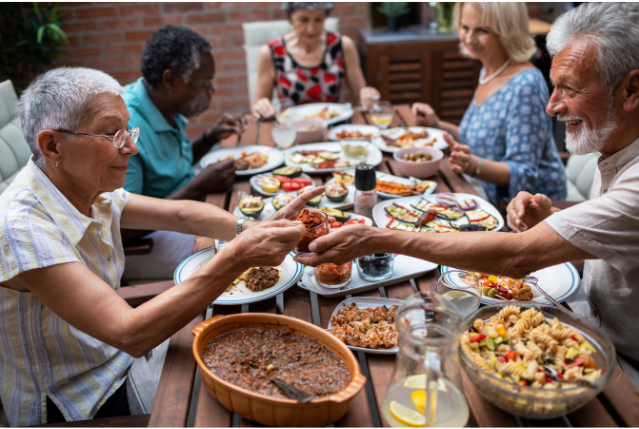 A group of seniors sharing a colorful meal outdoors, enjoying a lively conversation. A nod to the communal and cultural aspects of digital nomad retirement planning.
