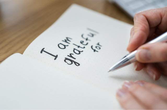 A close-up of a person writing “I am grateful for” in a journal, illustrating how gratitude practices can support mental clarity and emotional well-being in retirement.