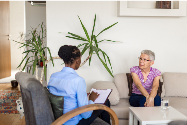A senior woman talking with a therapist in a cozy living room, showing the importance of seeking professional support to maintain emotional balance in retirement.