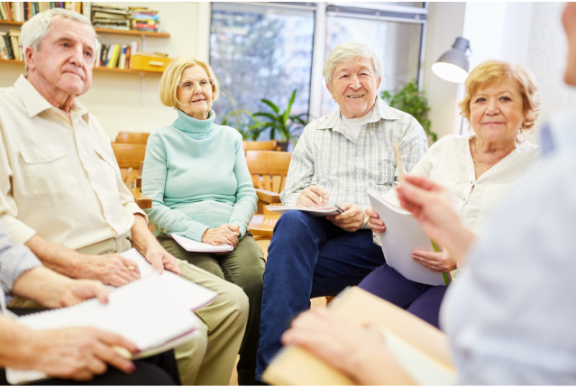 A group of older adults sitting with notebooks, participating in a group discussion to stay mentally engaged.