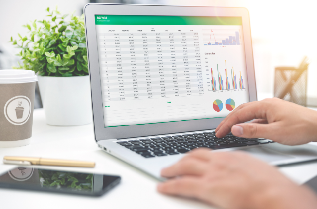 Hands working on a laptop displaying financial charts and spreadsheets.
