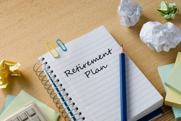 A notebook labeled 'Retirement Plan' surrounded by stationery and crumpled papers.
