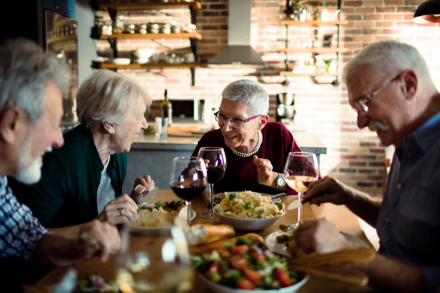 A group of seniors enjoying a meal together in a cozy, modern dining space. Highlighting the social aspects of retirement planning and connections.