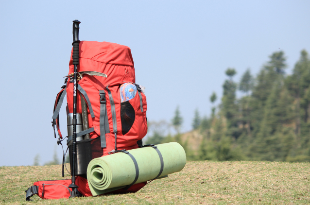 A red hiking backpack equipped with a rolled-up sleeping pad, ready for adventure. Ideal for retirees who prioritize exploration and mobility in their planning.