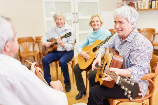 A group of seniors learning to play guitars in a class, highlighting how learning new skills can help keep your mind sharp in retirement.