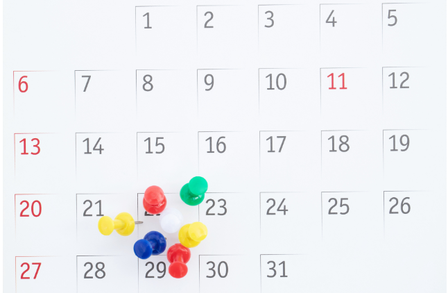 A monthly calendar with colorful pushpins marking specific days, helping retirees organize schedules and plan fulfilling daily activities.