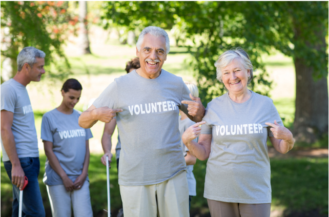 Retired couple proudly wearing 'Volunteer' shirts, showcasing the benefits of volunteering in retirement by staying engaged and active.