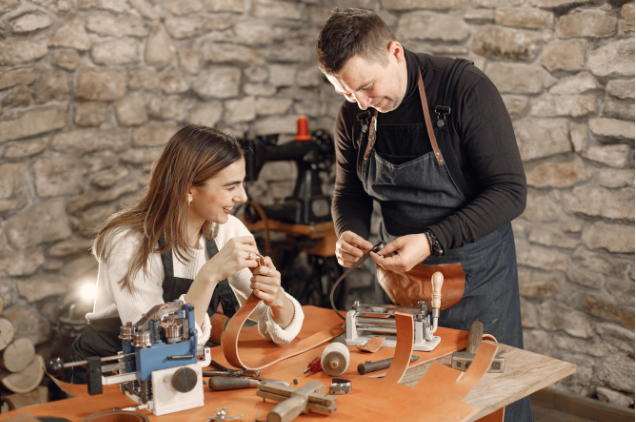 A creative duo working together on leather goods in a rustic workshop, demonstrating how craftsmanship can be transformed into a business after 50.