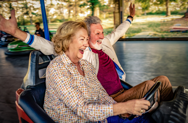 An energetic older couple joyfully riding bumper cars.