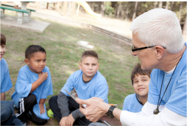 Retired volunteer mentoring children in an outdoor classroom, exemplifying how volunteering fosters purpose and intergenerational relationships in retirement.