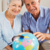 Portrait of senior couple holding a globe and smiling in living room