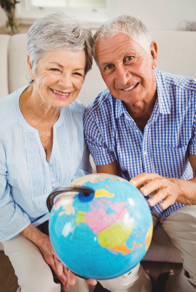 Portrait of senior couple holding a globe and smiling in living room