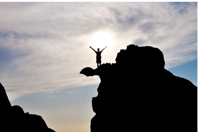 A silhouette of a person standing triumphantly on a mountain peak, representing overcoming the fear of irrelevance after retirement and embracing new opportunities.