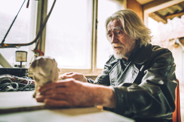 A senior man sculpting a piece of art in his workshop, highlighting how retirees are exploring creative passions and craftsmanship as part of an anti-retirement lifestyle.