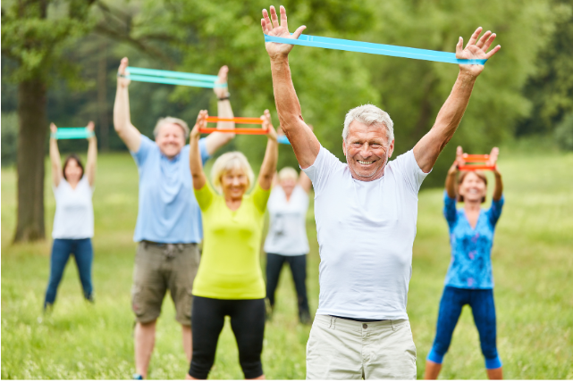 A group of active seniors participating in an outdoor resistance band workout, illustrating the importance of fitness and wellness in maintaining a vibrant anti-retirement lifestyle.