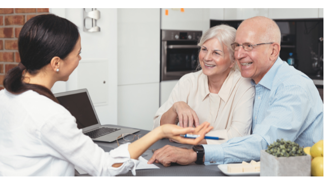 A happy senior couple meeting with a financial advisor at home, discussing financial planning strategies to support a flexible and fulfilling anti-retirement lifestyle.