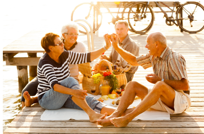 A group of active seniors sharing a joyful picnic on a dock, celebrating friendships and adventure.