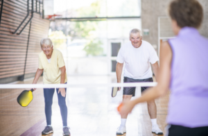 A fun and energetic group of older adults playing pickleball.