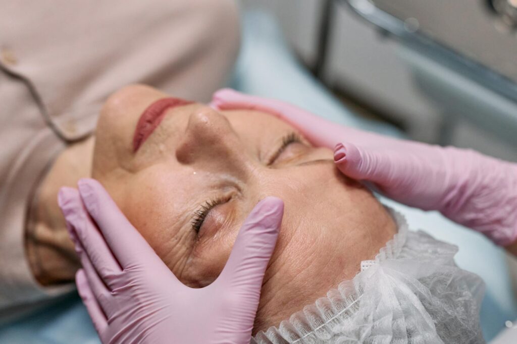 A senior woman relaxing while receiving a facial treatment.