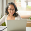A mature woman working on her laptop from home, representing the flexibility and independence of consulting after 50.
