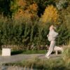 Older woman jogging outdoors in a park, staying active and healthy—one of many energizing things to do in retirement.