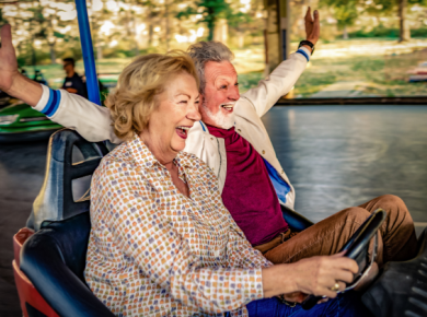 An energetic older couple joyfully riding bumper cars.